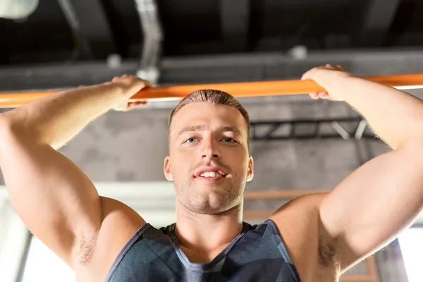 Muž cvičení na baru a dělat pull-up v tělocvičně — Stock fotografie