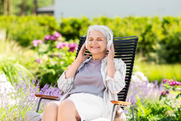 Mulher sênior feliz com fones de ouvido no jardim — Fotografia de Stock