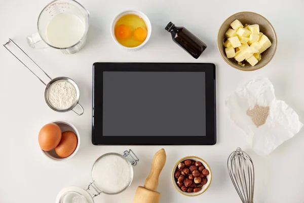 Tablet computer en koken ingrediënten op tafel — Stockfoto