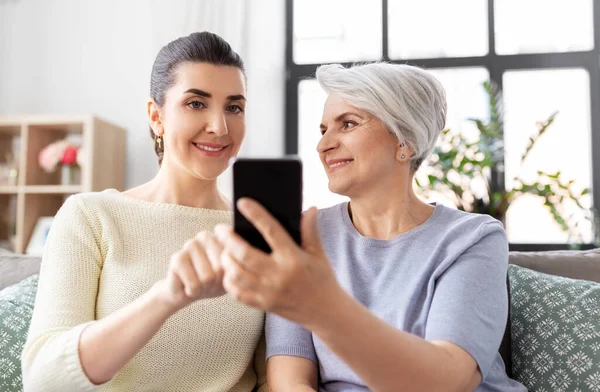 Figlia e madre anziana con smartphone a casa — Foto Stock