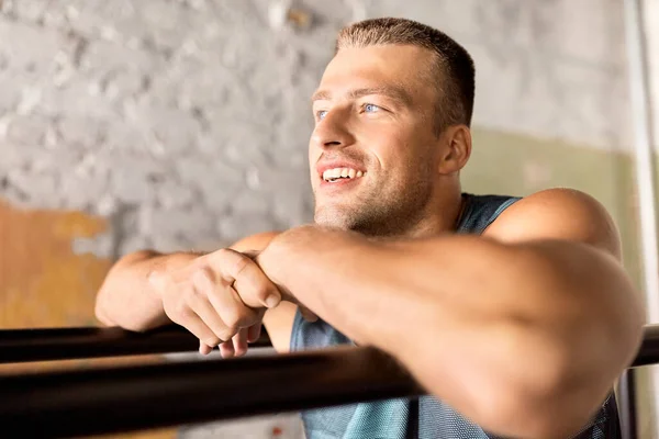 Jeune homme souriant dans les bars parallèles dans la salle de gym — Photo