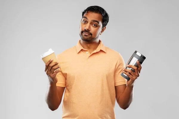 Mann vergleicht Thermobecher oder Tumbler mit Kaffeetasse — Stockfoto