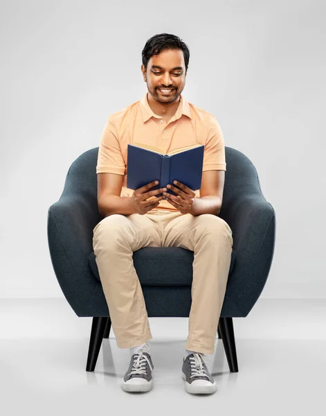 Feliz joven indio hombre leyendo libro en silla — Foto de Stock