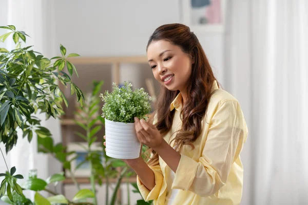 幸せなアジアの女性は家でポットで花と — ストック写真