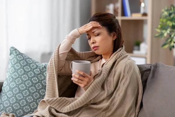 Ziek aziatische vrouw met hoofdpijn drinken thee thuis — Stockfoto