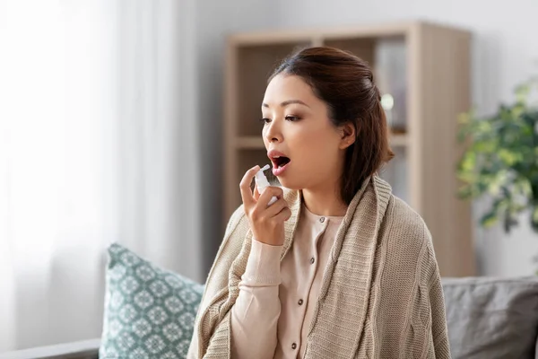Sjuk asiatisk kvinna som använder oral spraymedicin i hemmet — Stockfoto