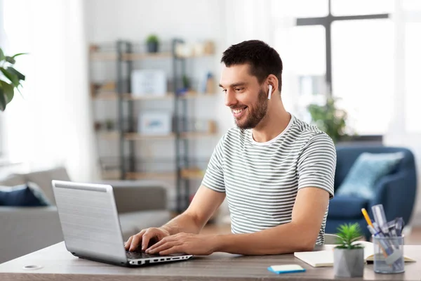 Homme avec ordinateur portable et écouteurs au bureau à domicile — Photo