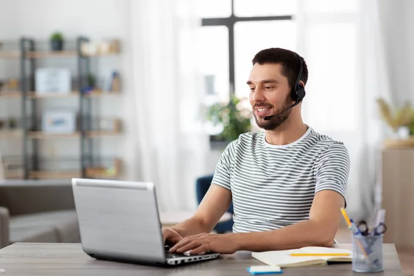 Uomo con auricolare e laptop che lavora a casa — Foto Stock