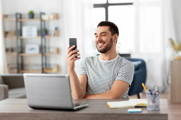 Mann mit Smartphone und Laptop im Home Office — Stockfoto