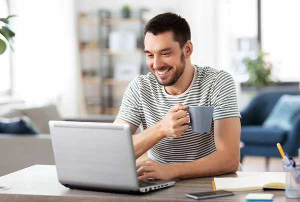 Man med bärbar dator dricka kaffe på hemmakontoret — Stockfoto