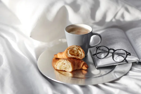 Croissants, Kaffee und Buch zu Hause im Bett — Stockfoto