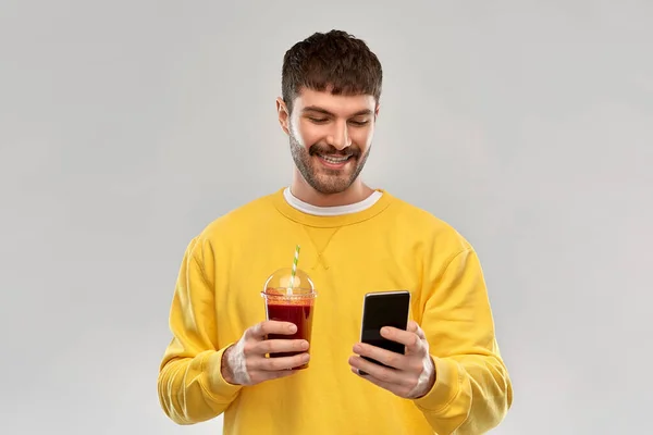 Ευτυχισμένος άνθρωπος με smartphone και χυμό ντομάτας — Φωτογραφία Αρχείου