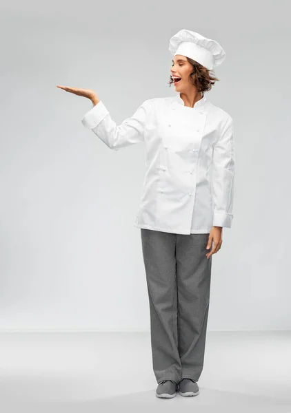 Sorridente chef femminile che tiene qualcosa a portata di mano — Foto Stock