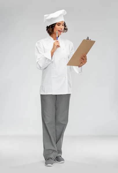 Glimlachende vrouwelijke chef in toque met klembord — Stockfoto