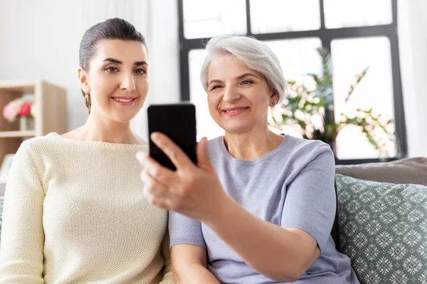 Starsza matka z córką robi selfie w domu — Zdjęcie stockowe