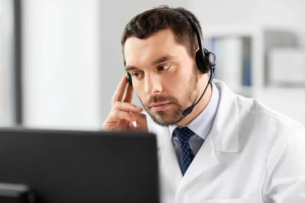 Médico varón con ordenador y auriculares en el hospital —  Fotos de Stock