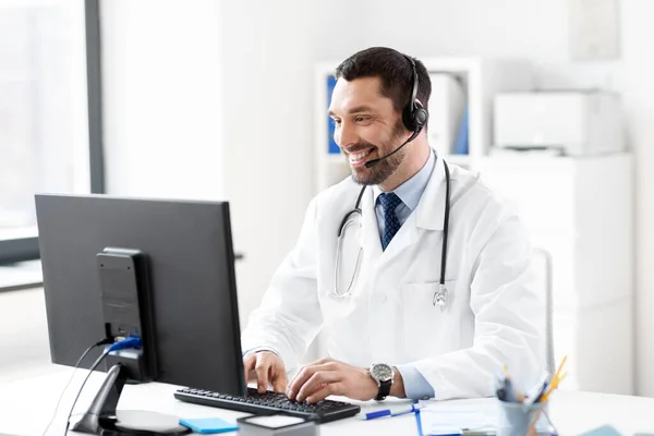 Glad läkare med dator och headset på sjukhus — Stockfoto