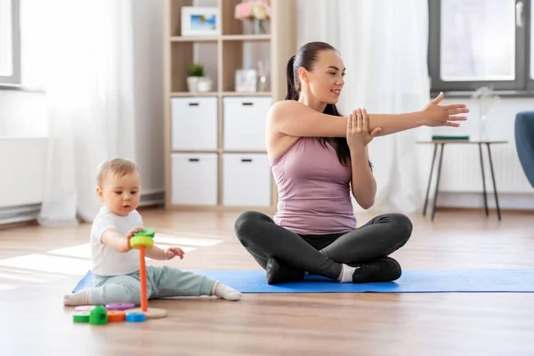 Madre feliz con el pequeño bebé haciendo ejercicio en casa —  Fotos de Stock