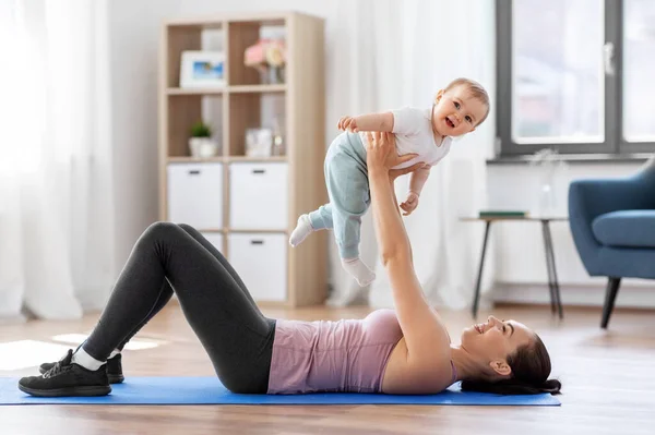 Glückliche Mutter mit kleinem Baby, das zu Hause Sport treibt — Stockfoto