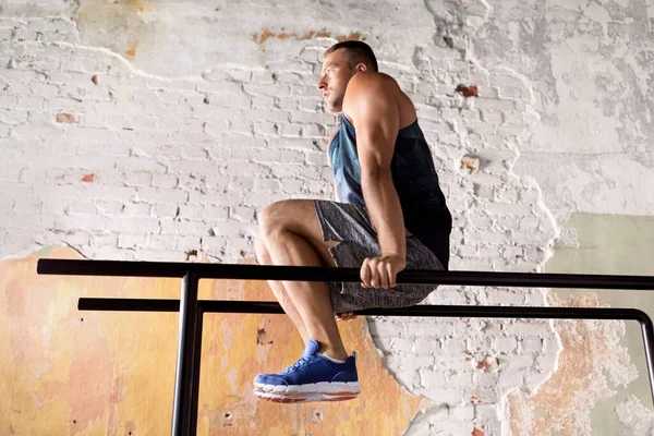 Man flexing abs on parallel bars in gym — Stock Photo, Image