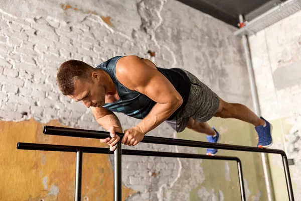 Hombre haciendo flexiones en barras paralelas en el gimnasio — Foto de Stock
