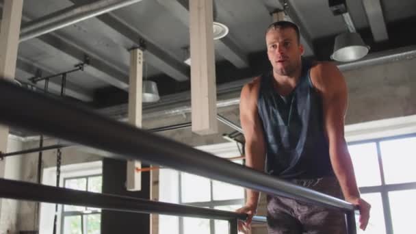 Homme fléchissant abdos sur des barres parallèles dans la salle de gym — Video