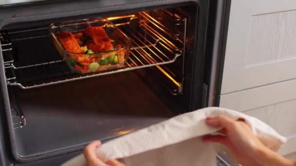 Vrouw koken voedsel in oven thuis keuken — Stockvideo