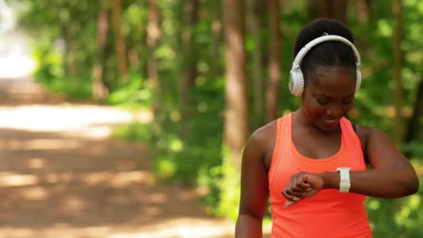 Afrykańska kobieta ze słuchawkami i inteligentnym zegarkiem — Wideo stockowe