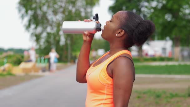 Mujer afroamericana bebiendo agua de la botella — Vídeos de Stock