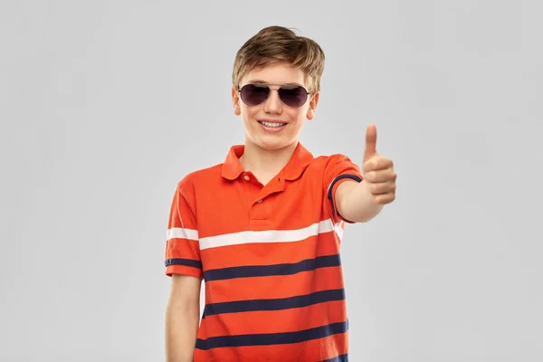 Усміхнений хлопчик в сонцезахисних окулярах показує великі пальці вгору — стокове фото