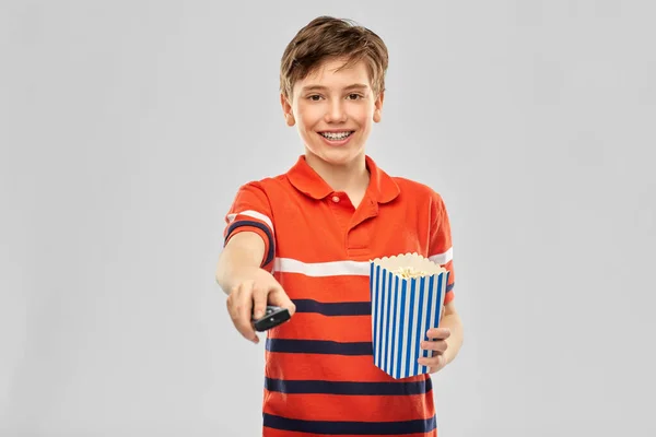 Улыбающийся мальчик с попкорном и пультом от телевизора — стоковое фото