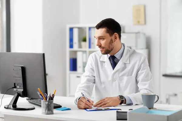 Médico com área de transferência e computador no hospital — Fotografia de Stock