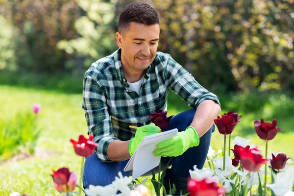 Homem com caderno e flores no jardim de verão — Fotografia de Stock