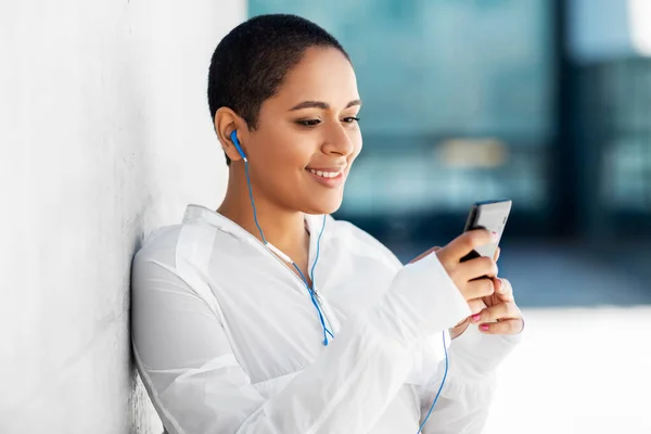 Mujer afroamericana con auriculares y teléfono —  Fotos de Stock