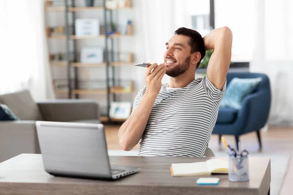 Hombre con el ordenador portátil llamando por teléfono en la oficina en casa — Foto de Stock