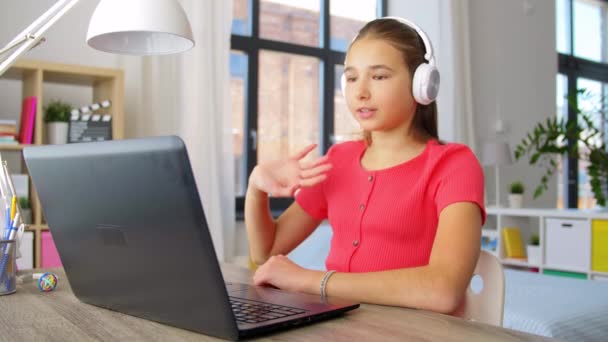 Menina em fones de ouvido com computador portátil em casa — Vídeo de Stock