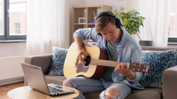 Man in headphones with laptop playing guitar — Stock Video