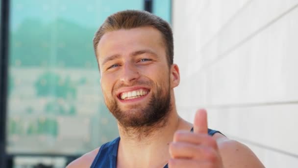 Портрет улыбающегося молодого человека, показывающего большие пальцы вверх — стоковое видео