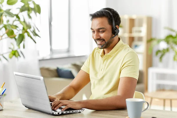 Hombre indio con auriculares y portátil trabajando en casa —  Fotos de Stock