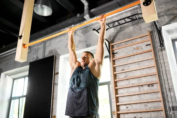 Hombre haciendo ejercicio en la barra y haciendo pull-ups en el gimnasio — Foto de Stock