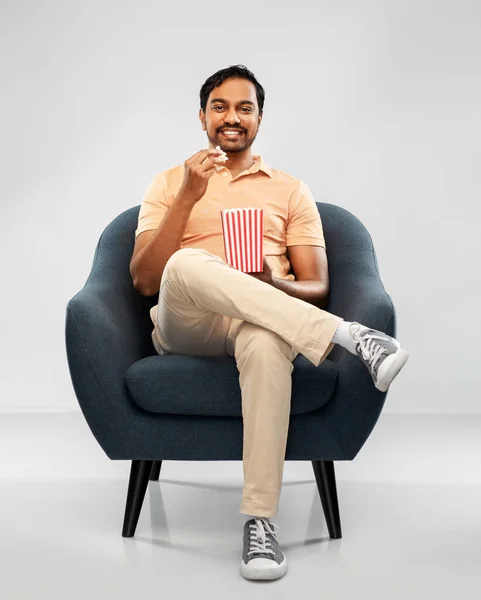 Glad leende indian man äter popcorn i stolen — Stockfoto