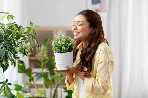 幸せなアジアの女性は家でポットで花と — ストック写真