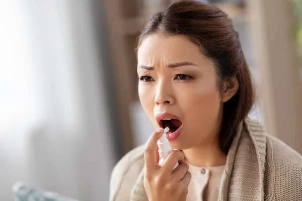 Malato asiatico donna utilizzando orale spray medicina a casa — Foto Stock