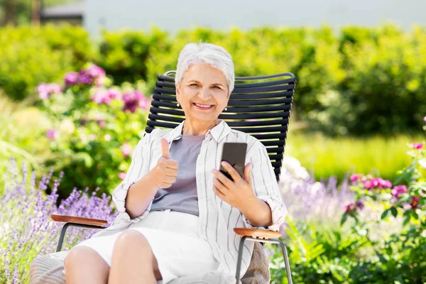 Szczęśliwa starsza kobieta z telefonem w ogrodzie letnim — Zdjęcie stockowe