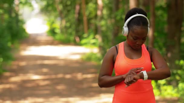Africká žena se sluchátky a chytrými hodinkami — Stock video