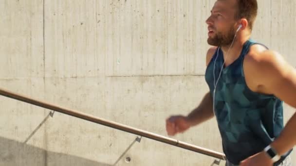 Mladý muž ve sluchátkách běžící nahoře — Stock video