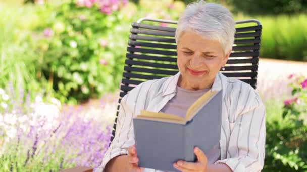 Glückliche Seniorin liest Buch im Sommergarten — Stockvideo