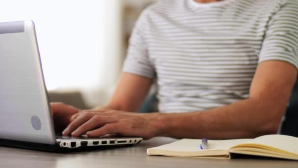 Άνθρωπος με σημειωματάριο και φορητό υπολογιστή στο γραφείο στο σπίτι — Αρχείο Βίντεο