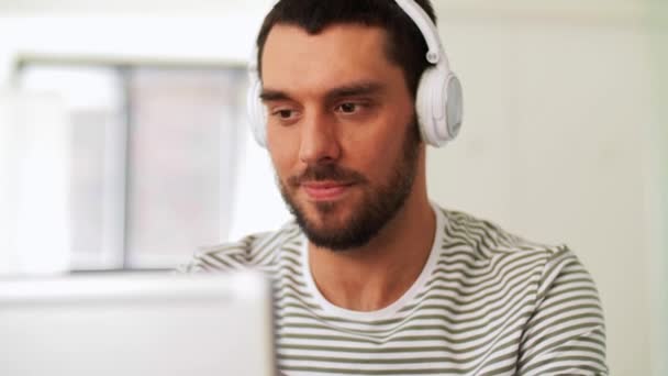 Людина в навушниках з ноутбуком працює вдома — стокове відео