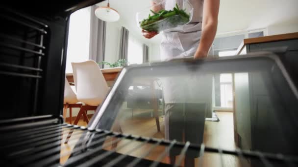 Vrouw koken voedsel in oven thuis keuken — Stockvideo